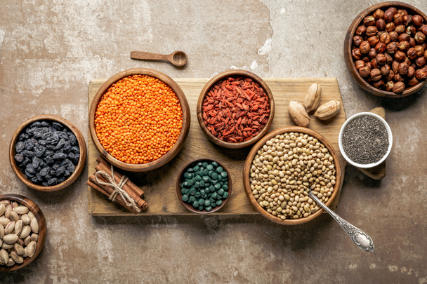 flat lay of wooden board with legumes, goji berries and healthy ingredients with rustic background - Photo, Image