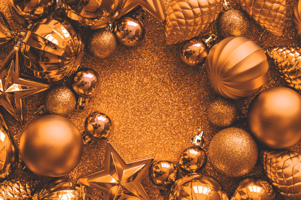 Golden Christmas frame. Christmas balls, stars, cones and hearts on golden sparkles background. Flat lay. Top view. Copy space. Toned - Photo, Image