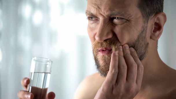 Man rinsing tooth with water, hypersensitivity, sharp dental pain, gingivitis - Φωτογραφία, εικόνα