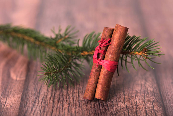 Pine branch with cinnamon on wooden background. Christmas concept - Фото, изображение