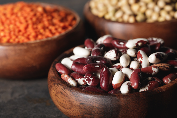 close up of beans in wooden bowl with legumes on background - Foto, immagini