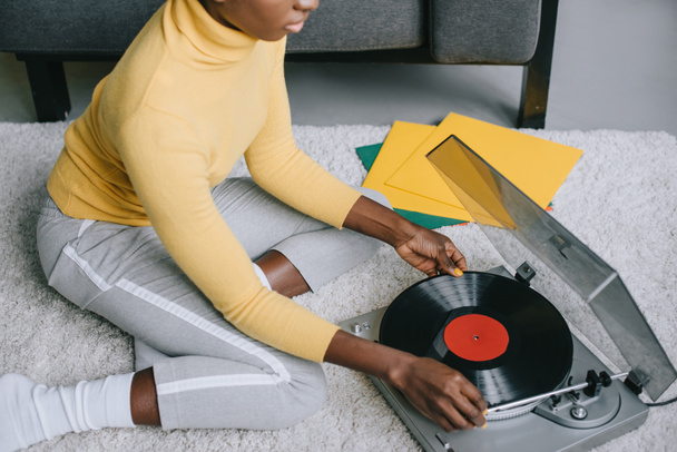cropped view of african american woman using record player on carpet - Foto, afbeelding