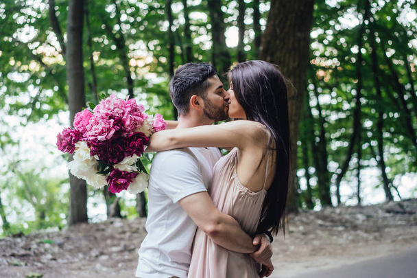 Молодая пара целуется на дороге в летнем парке
. - Фото, изображение