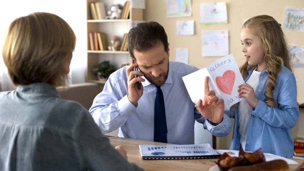 Father ignoring daughter with greeting card, talking on phone, indifference - Фото, зображення