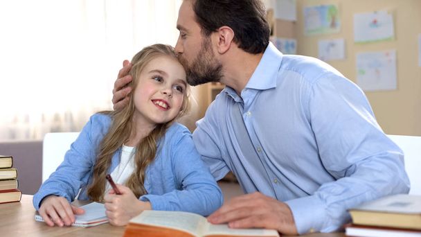 Proud father doing homework together with his daughter, education, family care - Fotoğraf, Görsel