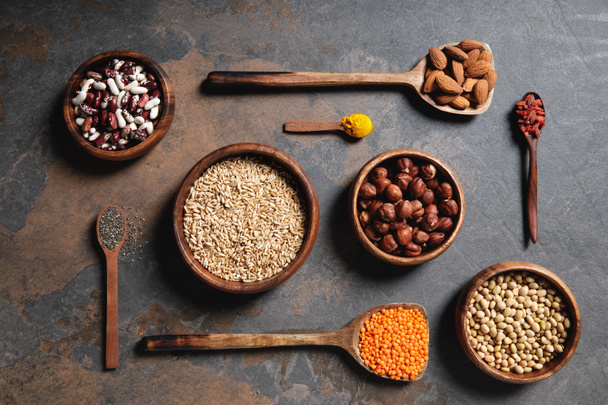 top view of wooden bowls and spoons with superfoods, legumes and grains on table - Photo, Image