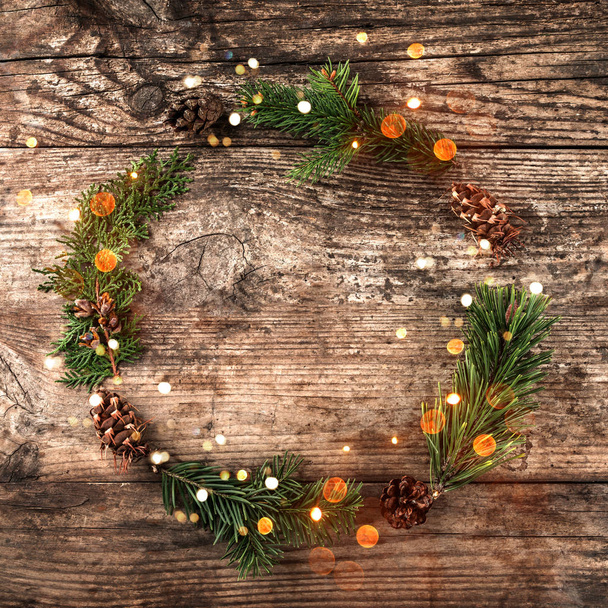 Weihnachtskranz aus Tannenzweigen, Zapfen, roter Dekoration auf Holzgrund mit Schneeflocken. Weihnachten und ein gutes neues Jahr Thema. flache Lage, Draufsicht - Foto, Bild