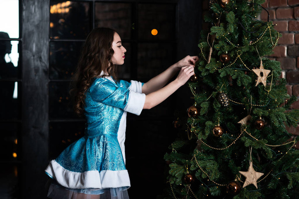 Russian Christmas characters snow maiden. Girl in Christmas costume posing near the Christmas tree - Foto, imagen