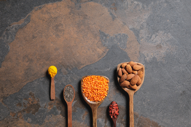 flat lay of arranged wooden spoons with superfoods, red lentils and turmeric on table with copy space - Photo, Image