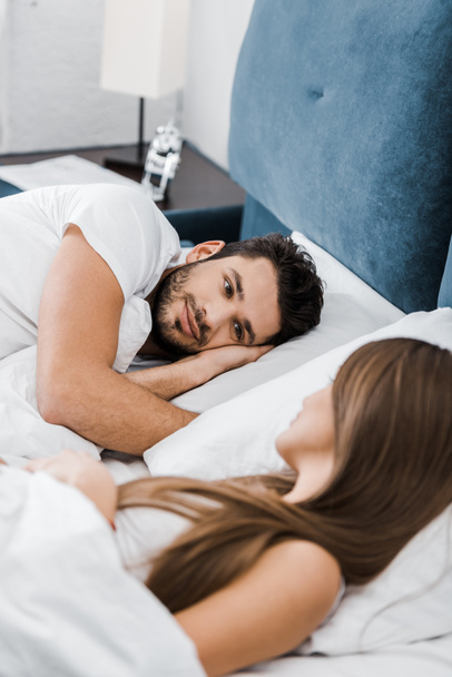handsome man lying in bed and looking at girlfriend - Φωτογραφία, εικόνα