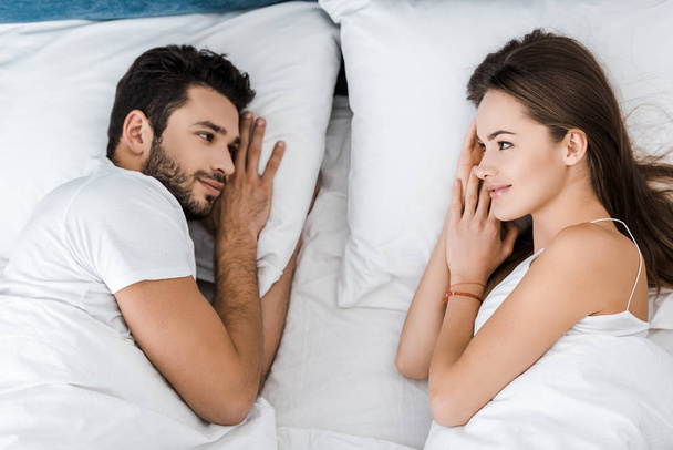 top view of young couple lying in bed and looking at each other - Foto, imagen
