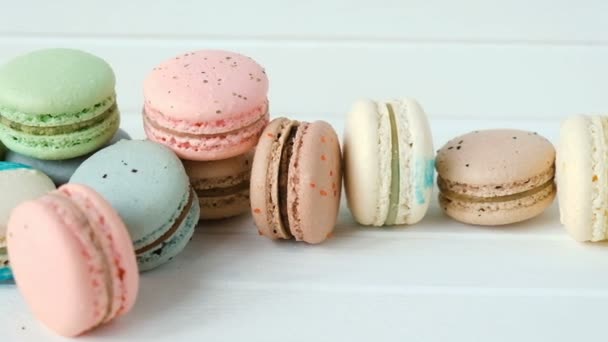 Multicolored macaroons or macarons lie on a white wooden background, a row of almond cookies - Footage, Video