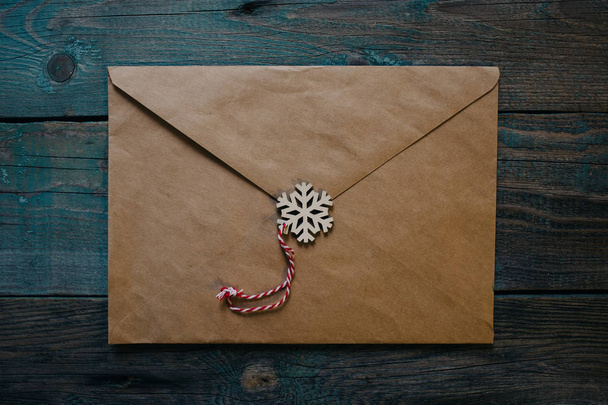 letter to Santa Claus, envelope with wooden Christmas decor in the form of wax seal, dark wooden background - Foto, imagen