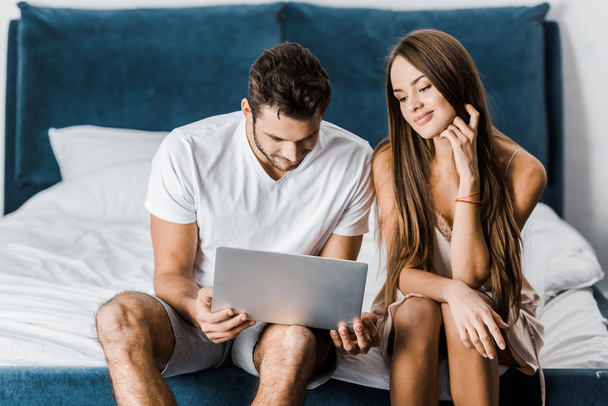 young couple in pajamas using laptop in bedroom - Photo, Image