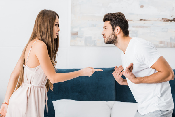 young attractive woman pointing with finger angrily at stressed gesturing man - Фото, зображення