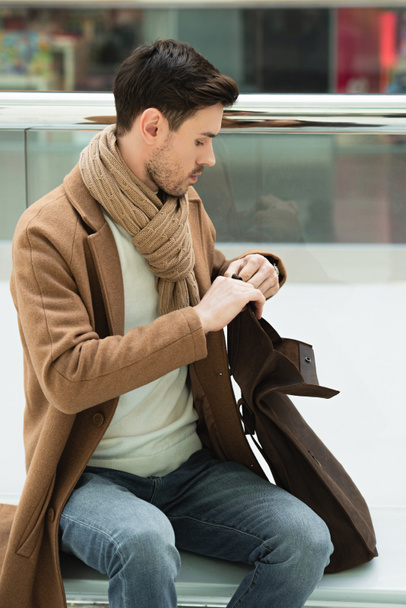 handsome man sitting on bench and opening bag - 写真・画像