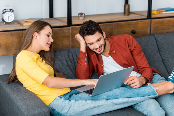 young attractive girl showing something on laptop to smiling boyfriend - Photo, Image