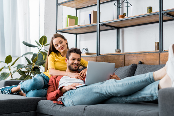 jeune couple heureux reposant sur un canapé avec ordinateur portable
 - Photo, image