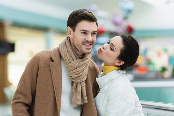 привлекательная девушка целуется улыбающийся мужчина в торговом центре
 - Фото, изображение