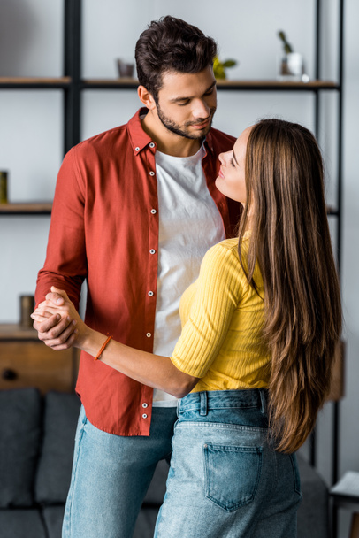 selective focus of happy bearded man dancing with girlfriend in living room - Photo, Image