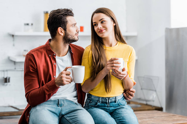 happy woman looking at boyfriend and holding cup - Photo, image