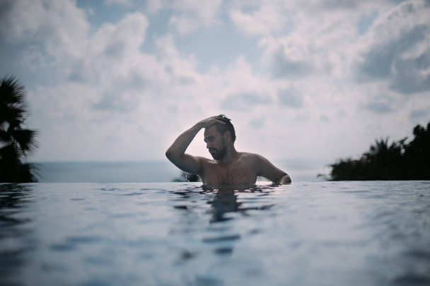 Retrato de un joven guapo en una piscina al aire libre. Tipo atractivo con barba al lado de la piscina
 - Foto, Imagen