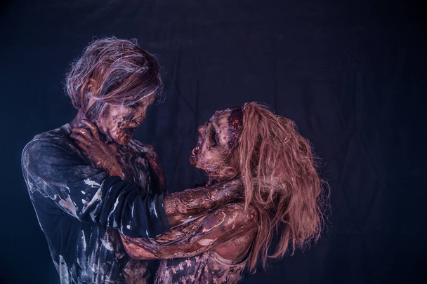 Zombie couple posing together against misty dark background - Foto, Imagen