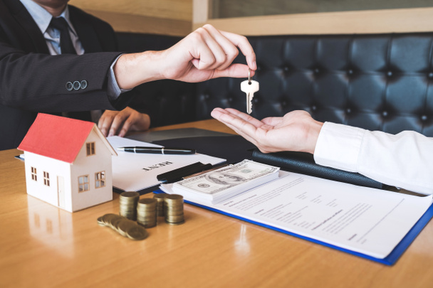 Agent nieruchomości dając klucze do domu klienta po podpisaniu umowy nieruchomości z zatwierdzonym formularzem wniosku o kredyt hipoteczny, dotyczące oferty kredytu hipotecznego i ubezpieczeń mieszkaniowych. - Zdjęcie, obraz