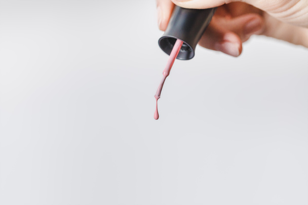 cropped view of woman holding brush with pink nail polish isolated on grey - Photo, Image