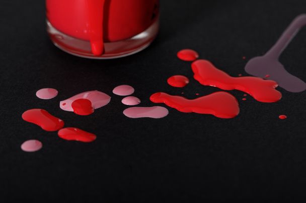 закрыть вид на бутылку лака для ногтей с красными и розовыми капли изолированы на черный
 - Фото, изображение