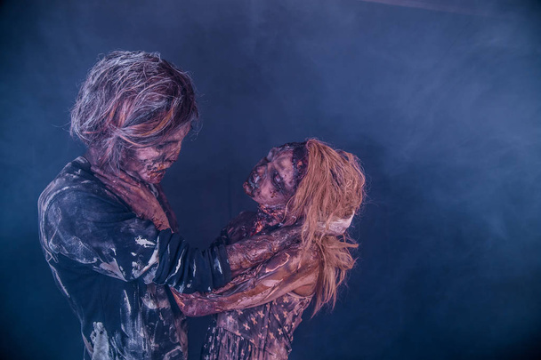 Zombie couple posing together against misty dark background - Photo, image