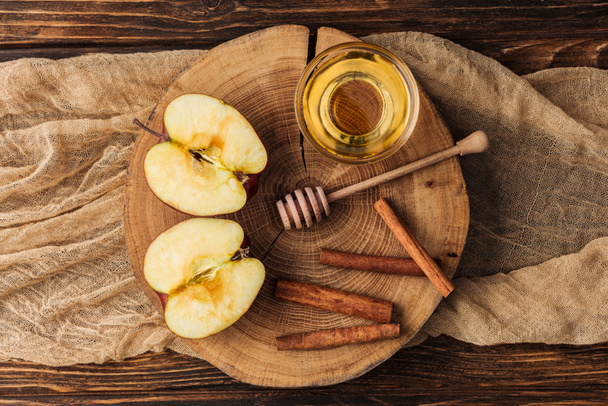 Baumstumpf mit geschnittenen Apfelhälften und Honig auf Holztisch - Foto, Bild