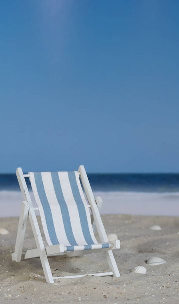 Cadeira listrada branca azul na praia
 - Foto, Imagem