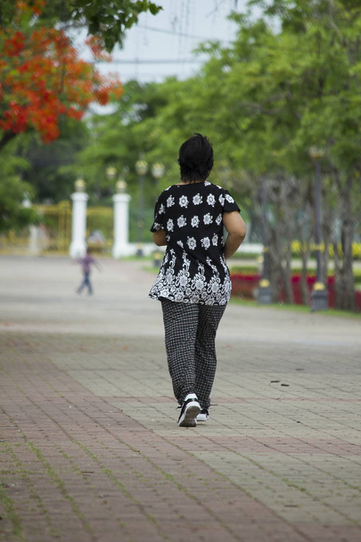 Egy idős nő öltözve, fekete, futás-a parkban. - Fotó, kép