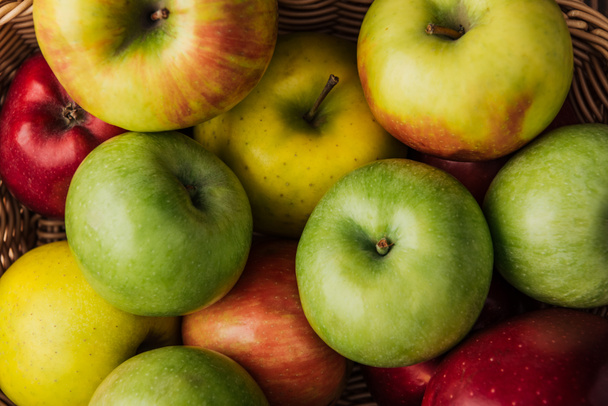 close up view of ripe multicolored apples in wicker basket - Fotografie, Obrázek
