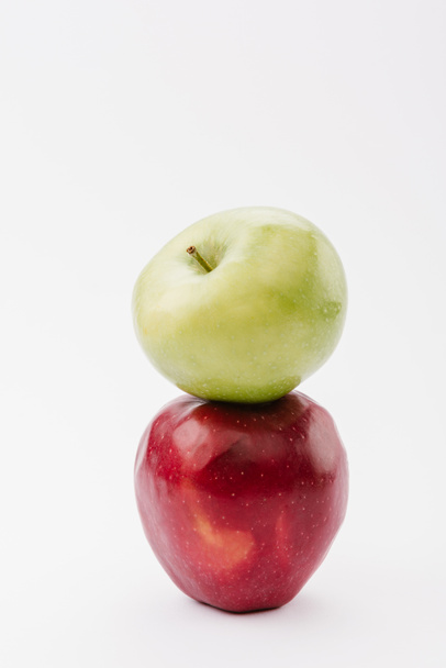 стопка з двох стиглих червоних і зелених яблук на білому тлі
 - Фото, зображення