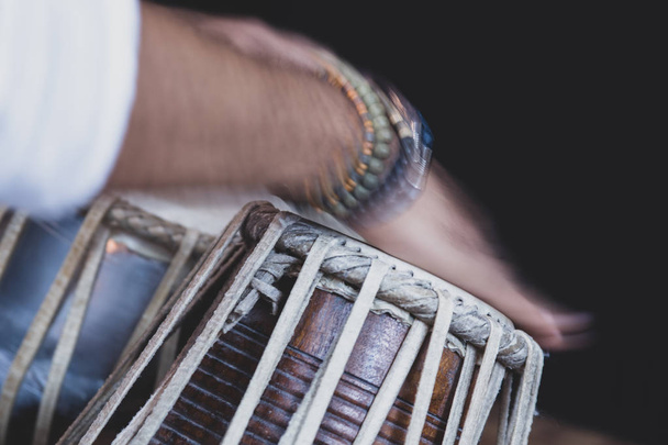 Изображение мужских рук (носящих бусы), играющих на инструменте Tabla - индийской классической музыке ударные - черный фон
. - Фото, изображение