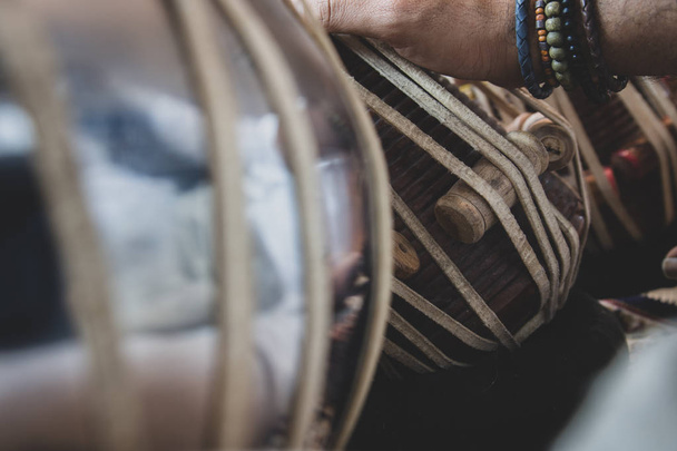 Image of a man's hands (wearing beads) playing the Tabla - Indian classical music percussion instrument - black background. - Photo, Image