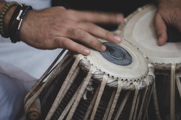 Image des mains d'un homme (portant des perles) jouant du Tabla - instrument de percussion de musique classique indienne - fond noir
. - Photo, image