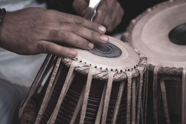 Image des mains d'un homme (portant des perles) jouant du Tabla - instrument de percussion de musique classique indienne - fond noir
. - Photo, image