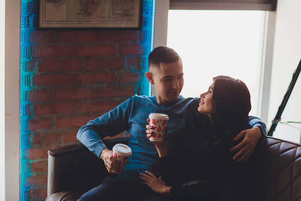 Beautiful couple sitting at romantic atmosphere looking each other, talking, smiling and drinking warm tea. Pregnant wife and her husband spanding time together at kitchen. Pragnancy family concept. - Foto, Bild