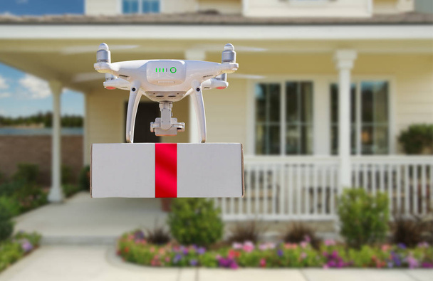 Quadrocopter-Drohne mit unbemanntem Flugzeugsystem (uav) liefert Box mit rotem Band nach Hause - Foto, Bild