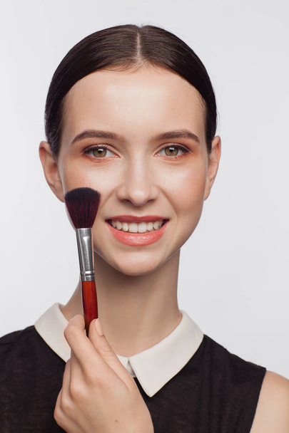 Beautiful woman holds makeup brush in her hand - Fotografie, Obrázek