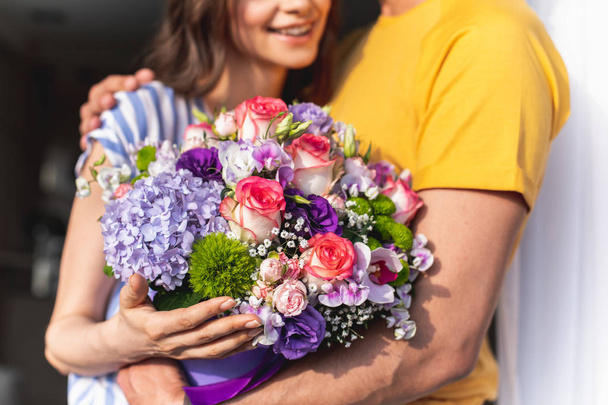 Man hugging happy young woman with bouquet - Fotó, kép