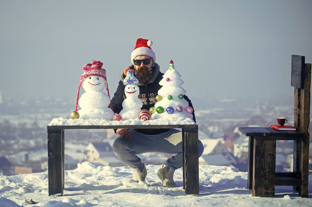Hipster sitting with snowmen and snow xmas tree on table - Fotografie, Obrázek