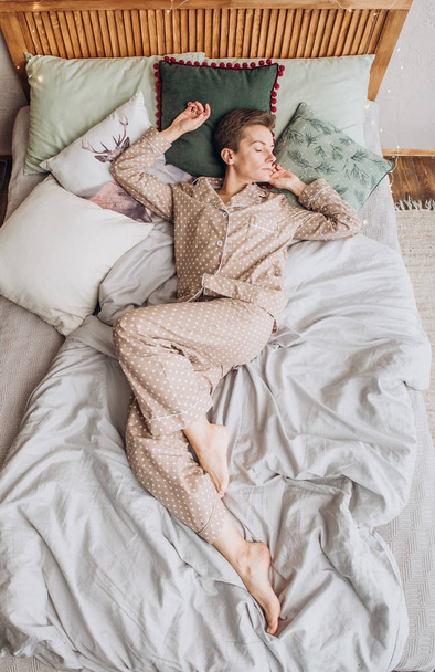 girl in pajamas sleeping on a bed with pillows decor christmas tree light - 写真・画像