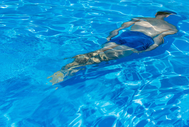 Κατάδυση άνθρωπος σε μια πισίνα με το μπλε νερό - Φωτογραφία, εικόνα