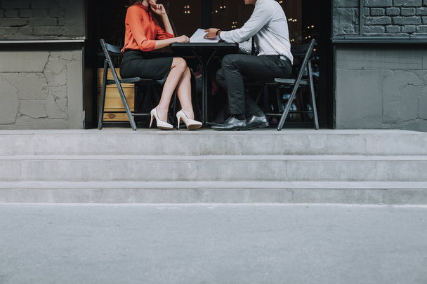 Concept of business meeting on fresh air. Portrait of office man and woman sitting in outdoor cafe and discussing work - Fotó, kép