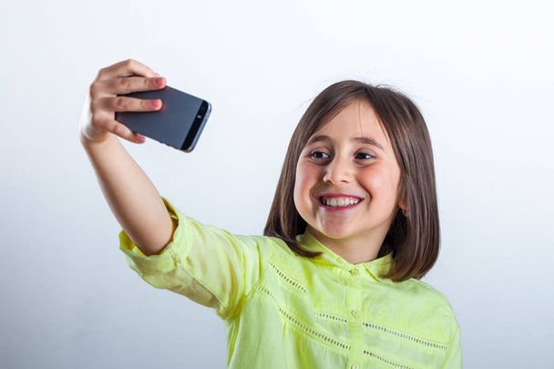 Jolie adolescente avec téléphone portable en studio. Selfie
. - Photo, image