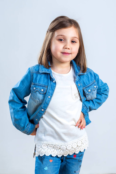 little girl in jeans posing for the camera in the studio. - Foto, Imagen